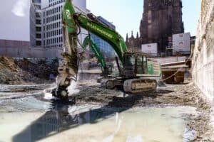 Baggerfräse im Einsatz – Baustellenfotografie Bagger fräst mit Spezialgerät Asphalt auf Baustelle – technische Baustellenaufnahme