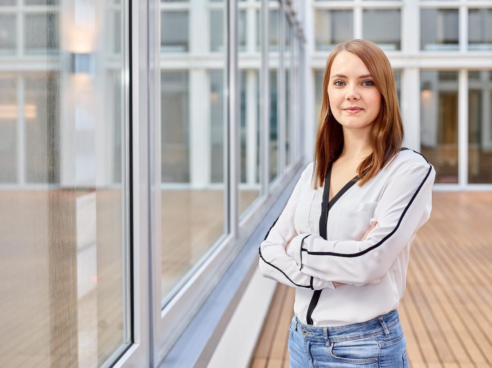 Businessfotografie in Hamburg – authentisches Porträt einer jungen Frau im modernen Büroflur