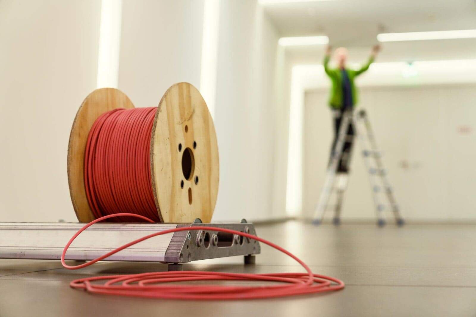 Installation kabeltrommel im Hintergrund ein Mann am arbeiten auf einer Leiter