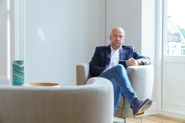 corporate-mann-sitzt Corporate Fotografie, Mann in einer Gesprächssituation in einem Sessel sitzend.