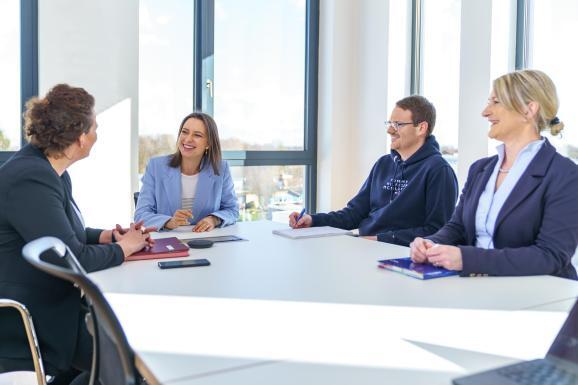 Corporate Fotografie in einer Besprechung. Vier Personen sitzen an einem Tisch