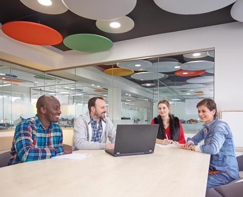 Corporatefotografie Hamburg – interdisziplinäres Team in moderner Besprechung mit Laptop und kreativen Deckenelementen