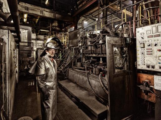 Industriefoto, Porträt eines Arbeiters in der Kupferproduktion neben einer Guss-Anlage in Hamburg