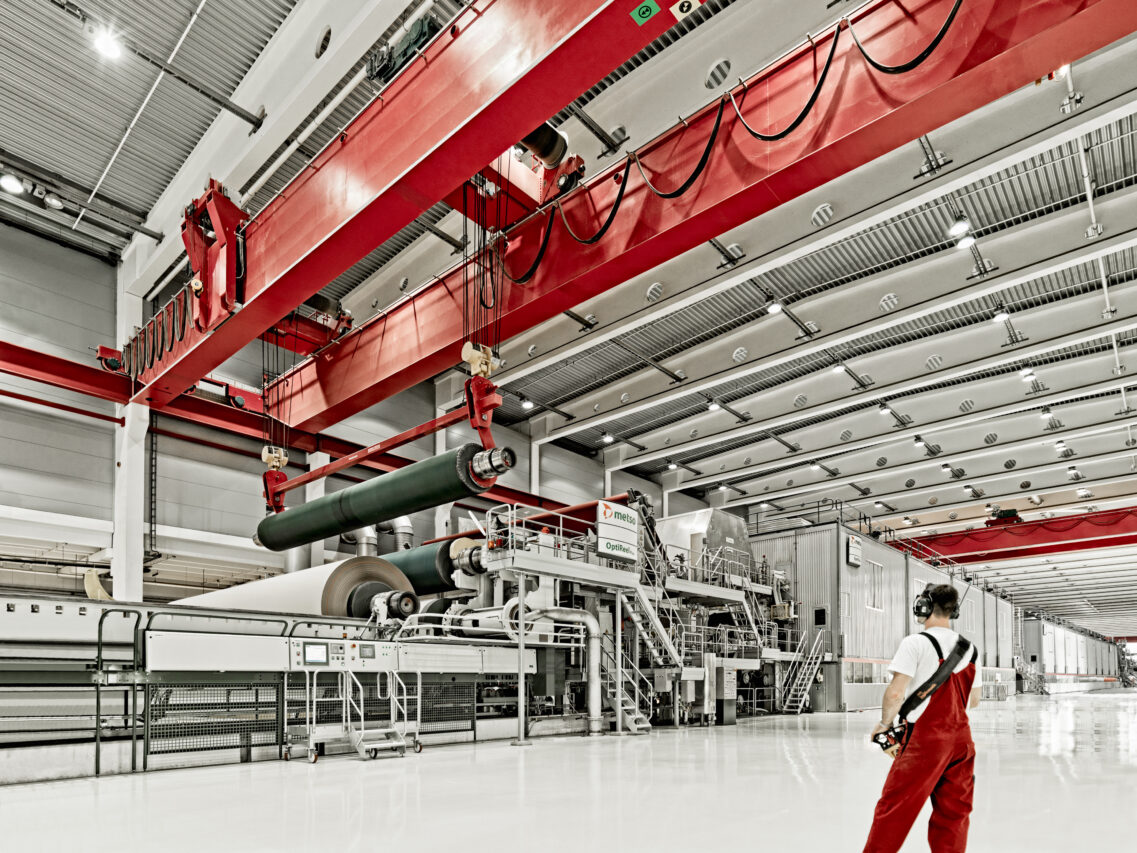 Kran hebt Papierrolle in Papierfertigung – industrielle Produktionsfotografie
