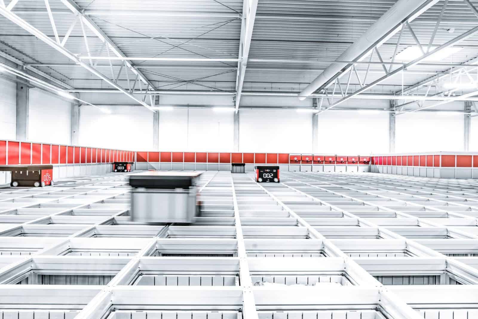 Logistikfotografie - automatisiertes kleinteillager von oben mit Entnahmewagen in Bewegung