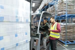 Gespräch im Lager Mitarbeiter im Gespräch neben einem Gabelstapler im Lager