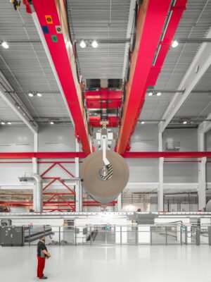 Kranführer mit Papier-Tambour Kranführer bewegt großen Papier-Tambour in der Produktionshalle – Industriefotografie von Erik Krüger.