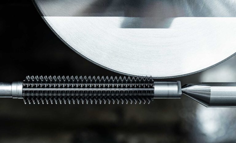 praezisions-werkzeugschleifen-industrielle-fertigung-metallbearbeitung Präzisionswerkzeugbau: Detailansicht beim Schärfen eines Metall-Gewindebohrers oder Fräswerkzeugs mit einer hochmodernen Schleifscheibe in der Metallbearbeitung.