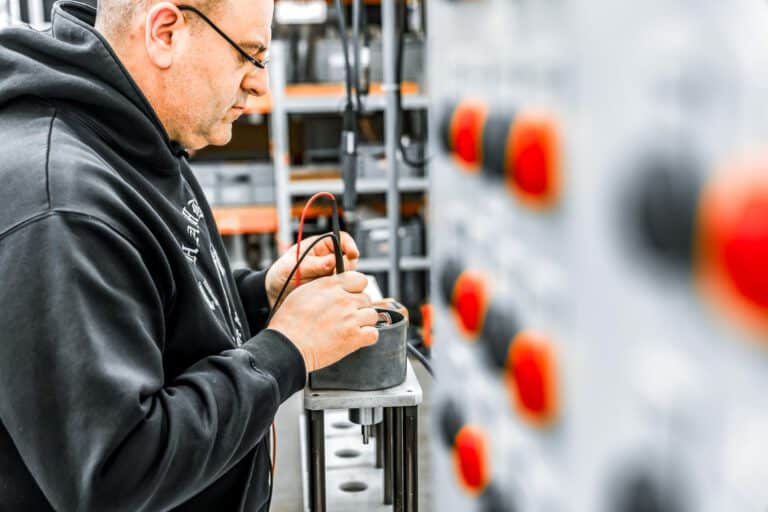 Messung Elektroanlage Elektrotechnik Fotografie – Mitarbeiter misst elektrische Werte an moderner Industrieanlage, präzise Darstellung von Produktion und Qualitätskontrolle