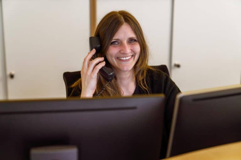 Rezeption Telefonat – Corporatefotografie Corporatefotografie – Mitarbeiterin telefoniert an moderner Rezeption, authentische Darstellung von Kundenservice und Unternehmenskommunikation